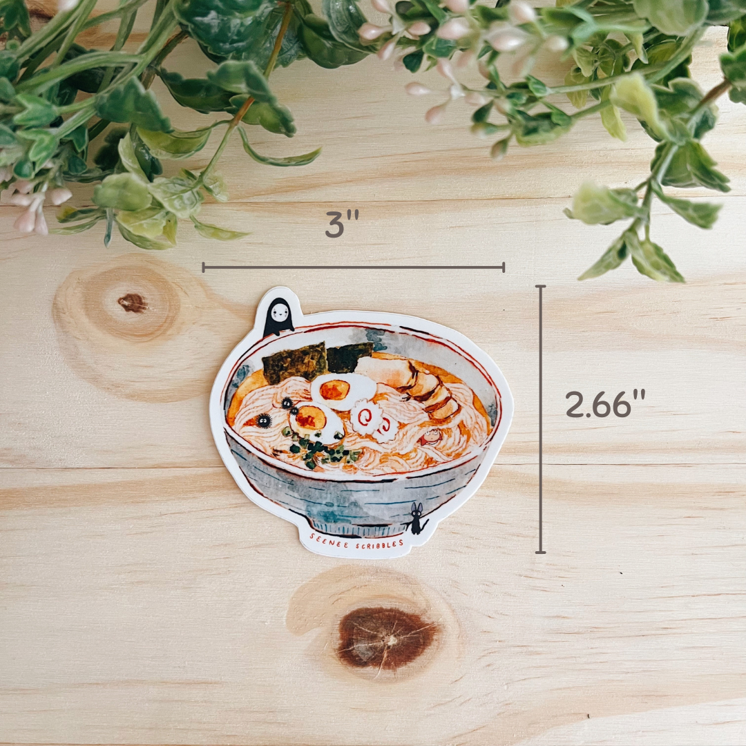 Watercolor painted sticker featuring various characters from Studio Ghibli films. The sticker is on a wooden desk with leaves at the top. Sticker's dimensions are shown: 3 inches wide, 2.66 inches tall.