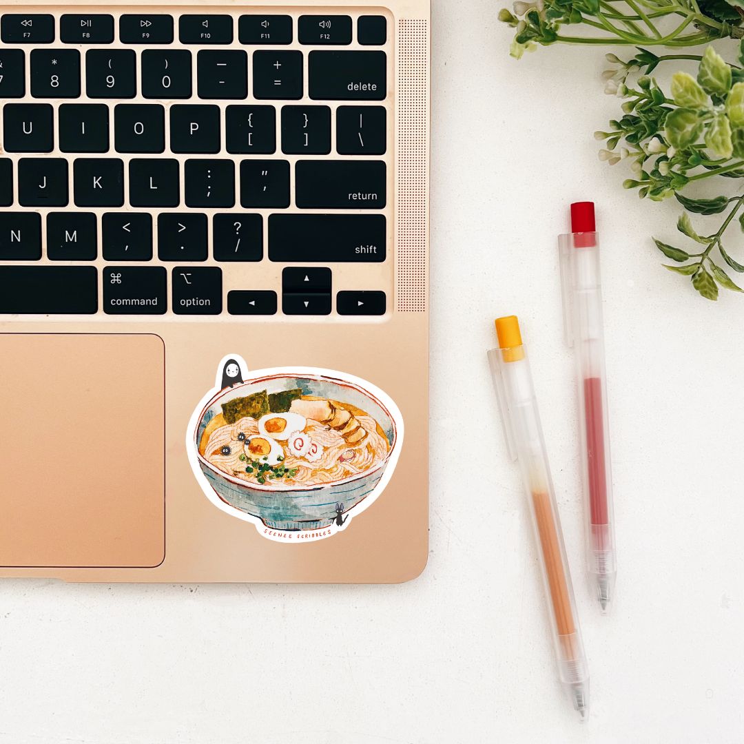 Watercolor painted sticker featuring various characters from Studio Ghibli films. The sticker is on the corner of a laptop.