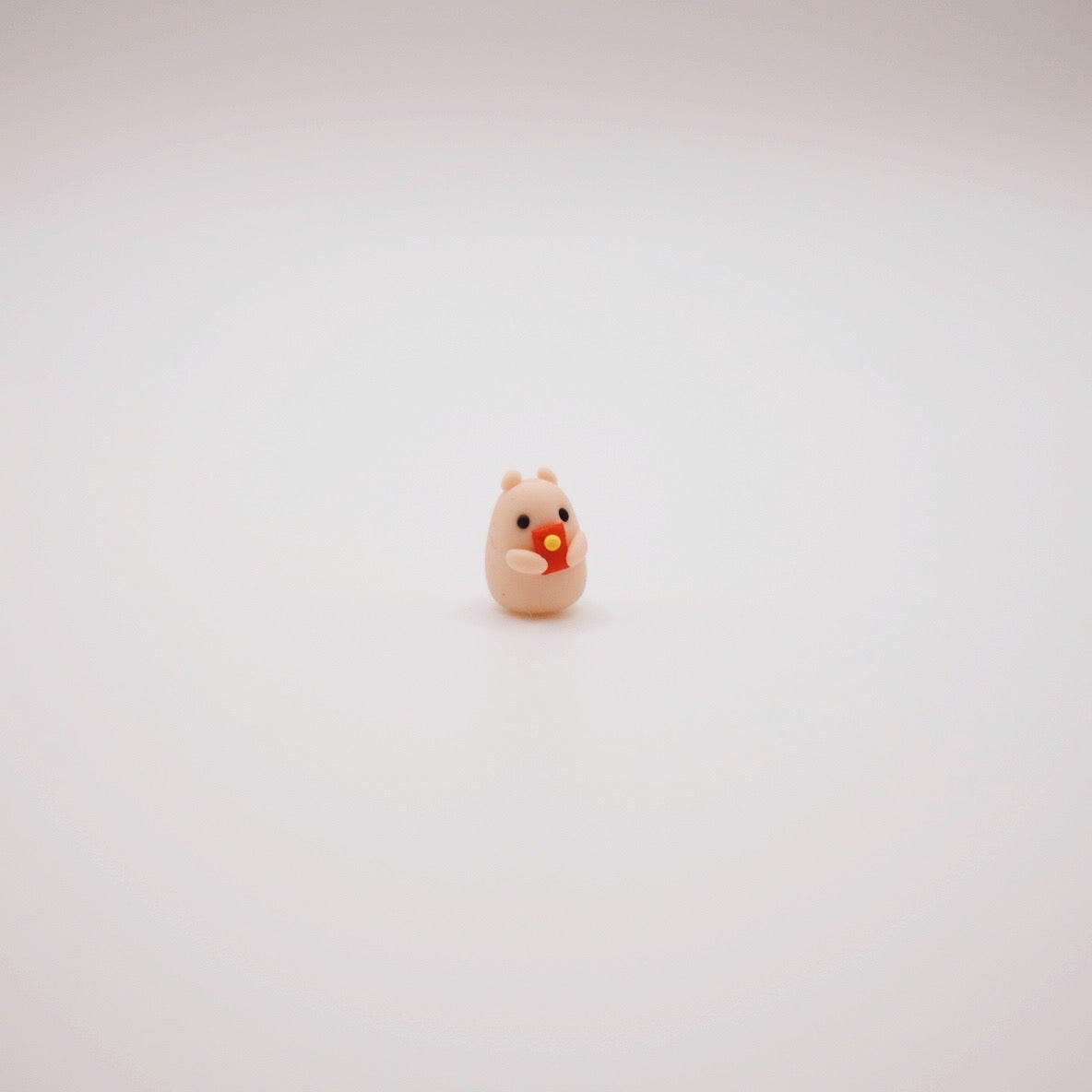 Tiny clay hamster holding a red envelope